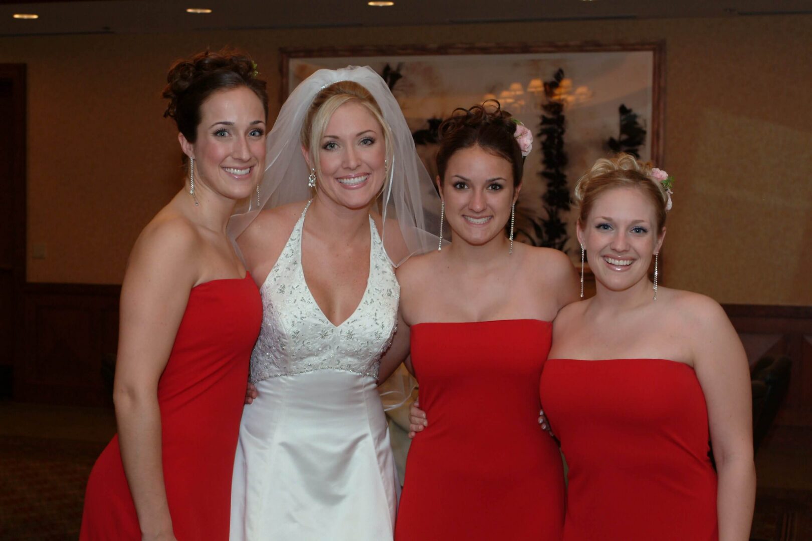 Bride with bridesmaids in red dresses smiling.