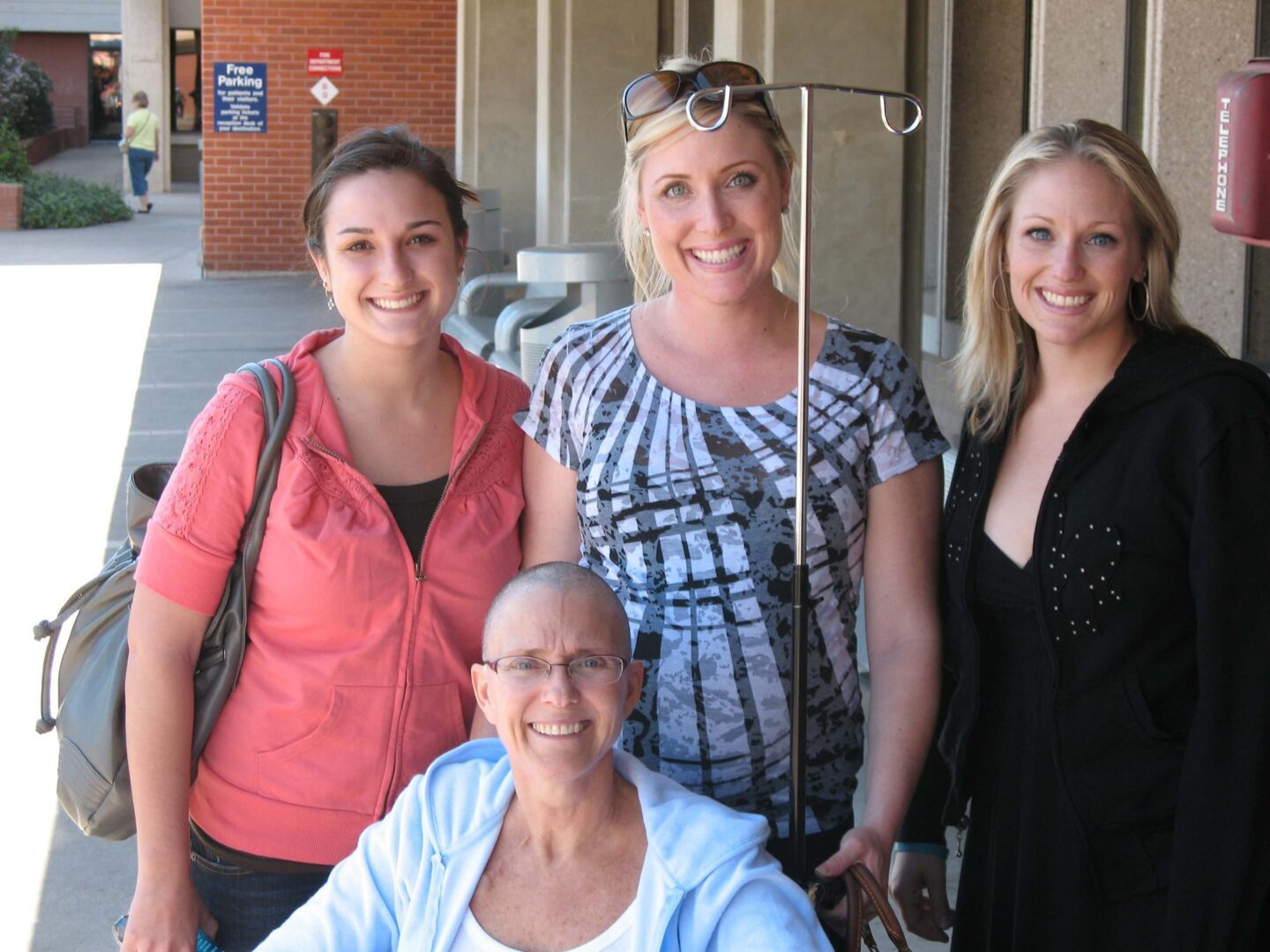 Four women smiling outside a building.