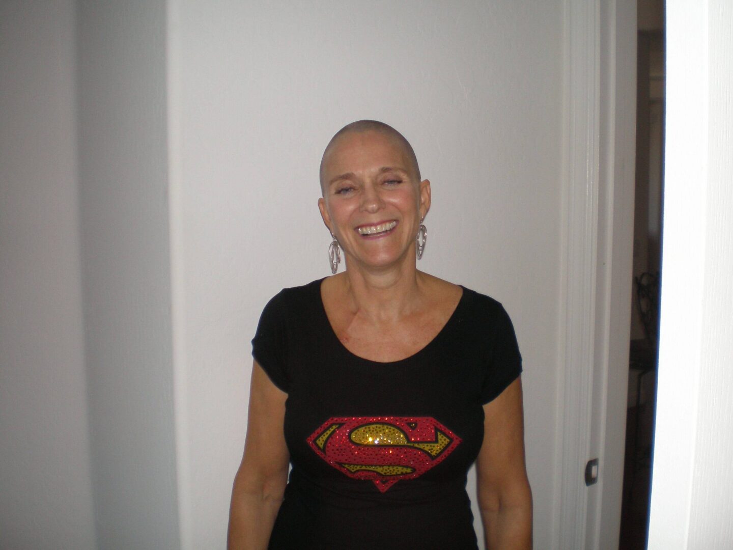 Smiling woman wearing Superman logo shirt.