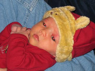 Baby in red onesie with yellow bear hat
