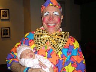 Clown in colorful costume holding sleeping baby