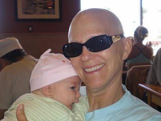 Smiling person in sunglasses cradling baby