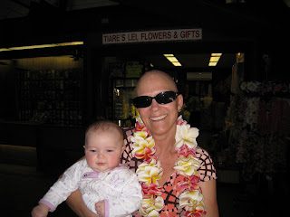 Smiling woman with lei and sunglasses holding baby