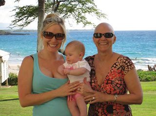Two women holding baby by ocean