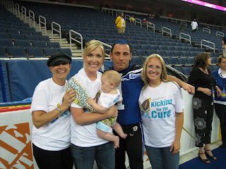 Four adults smiling, one holding baby at arena