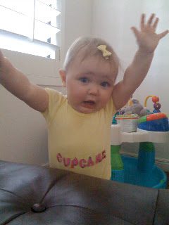 Baby in cupcake onesie raising arms