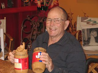Smiling man holding two jars of peanut butter