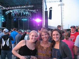 Three women smiling at outdoor concert