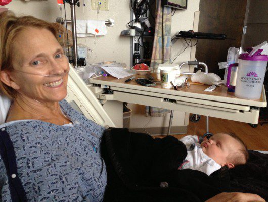 Woman in hospital bed with sleeping baby.