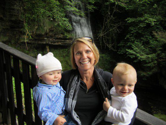 A woman and two children standing next to a waterfall, enjoying their time together.