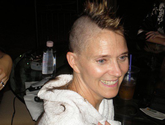 A woman with advanced ovarian cancer boldly showcases her shaved head, embracing her journey of strength and resilience.