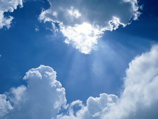 The sun shines through the clouds in a blue sky, symbolizing hope amidst the battle against ovarian cancer.