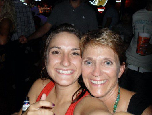 Two women posing for a photo at a bar.