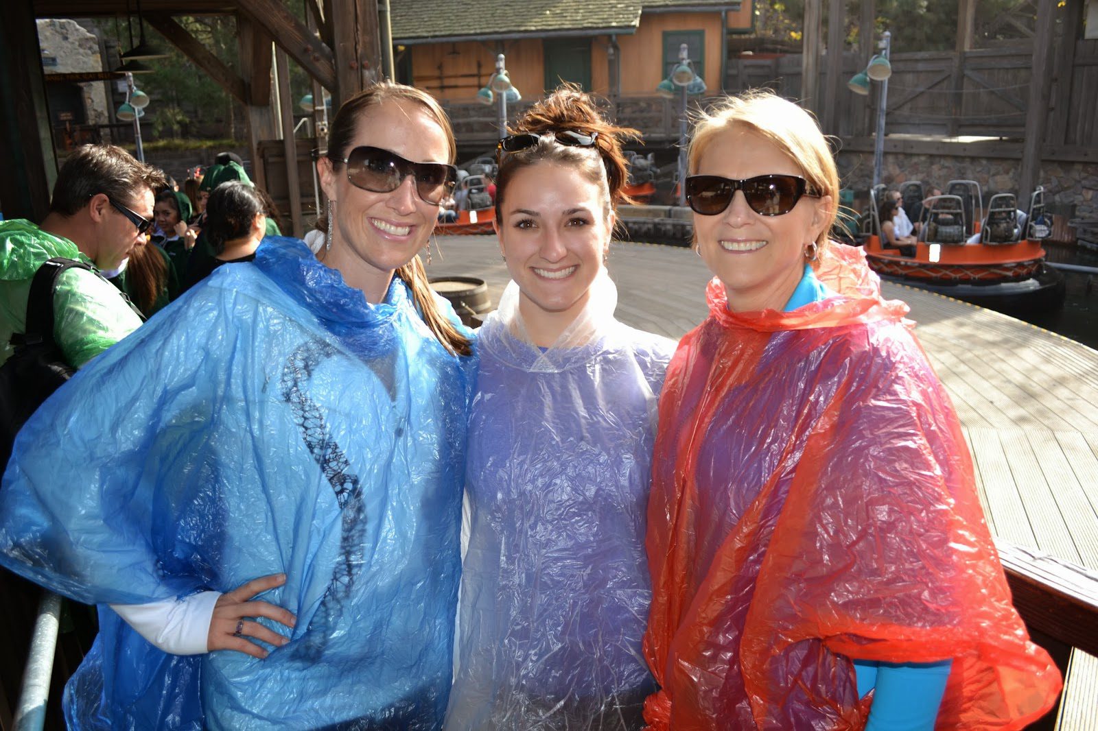 Three women in raincoats posing for a picture.