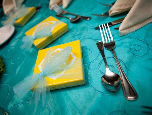 Yellow gift boxes on turquoise tablecloth.