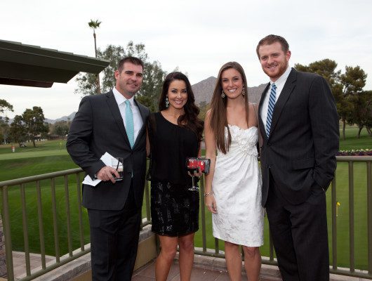 Four people smiling at outdoor event.