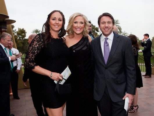 Three people smiling at an outdoor event.
