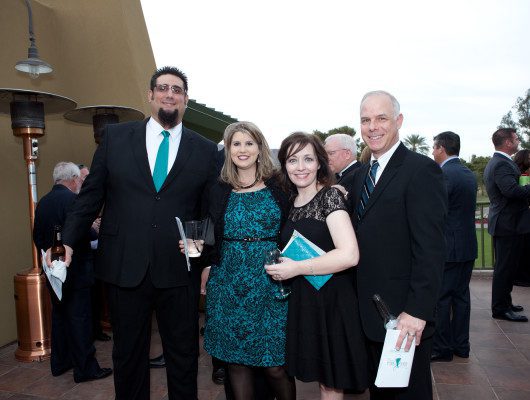 Four people posing at an outdoor event.