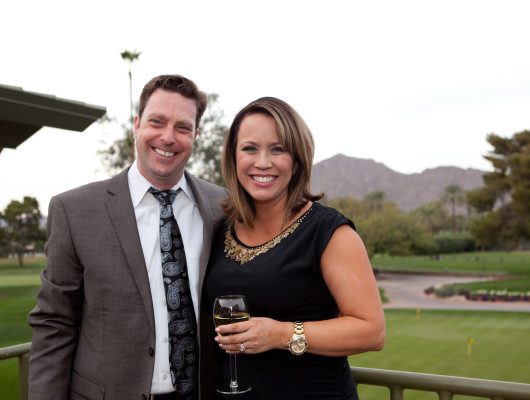 Smiling couple on a golf course balcony.