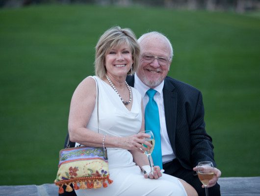 Smiling couple sitting outdoors with drinks.