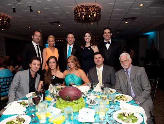 Group at formal dinner event with football centerpiece.