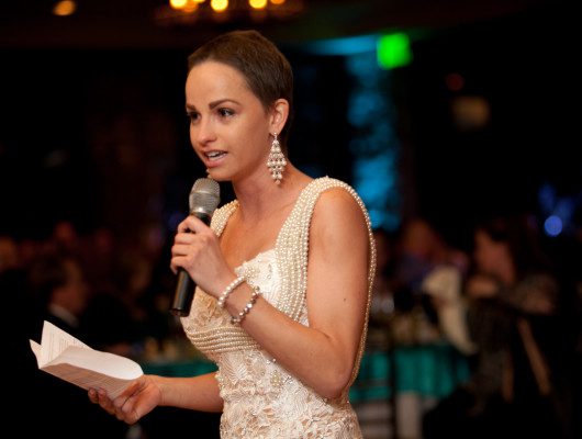 Woman speaking into microphone at event.