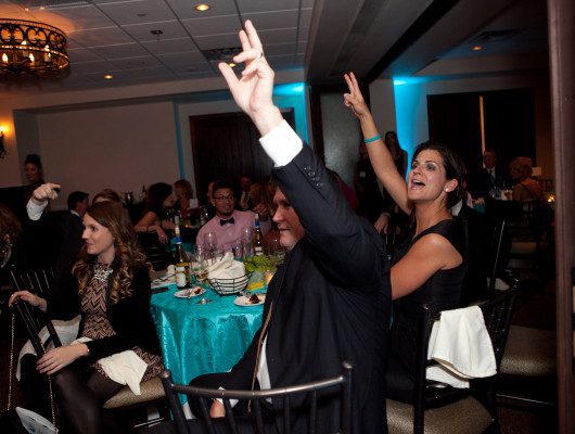 People raising hands at a formal event.