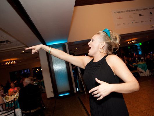 Woman enthusiastically gesturing at lively event.