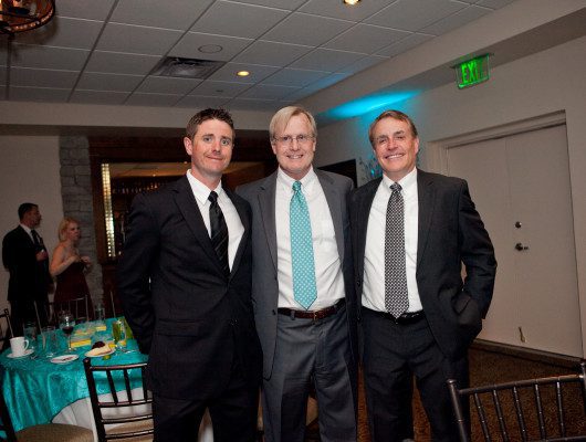Three men in suits at formal event.