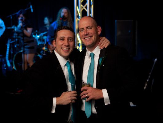 Two men smiling at a party.