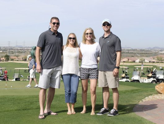 Four people posing on a golf course.