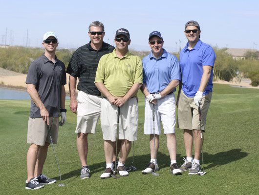 Five men posing on a golf course.
