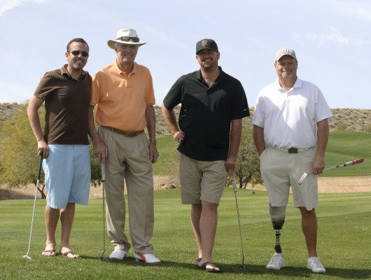 Four men standing on a golf course.