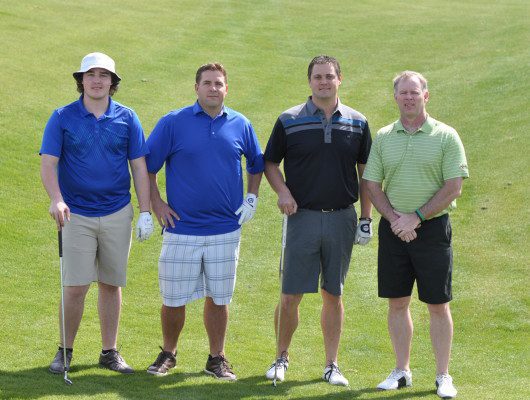 Four men standing on a golf course.