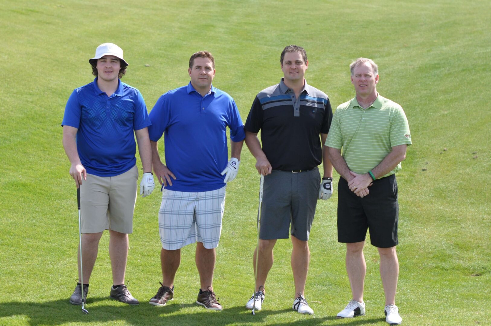 Four men standing on a golf course.