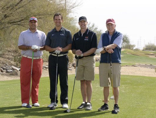Four men standing on a golf course.