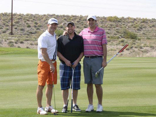 Three men posing on a golf course.