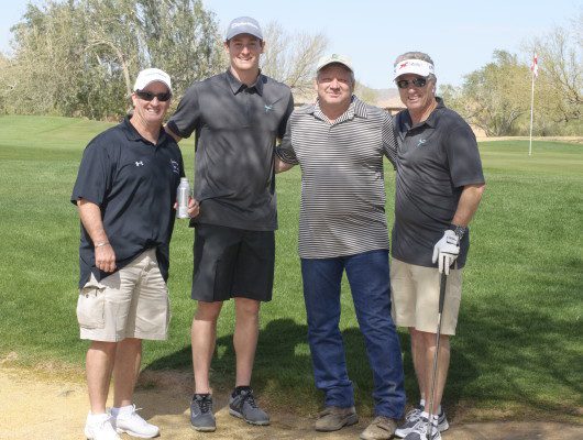 Four men standing on a golf course.