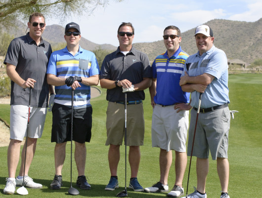 Five men posing on a golf course.