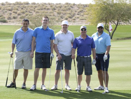 Five men posing on a golf course.