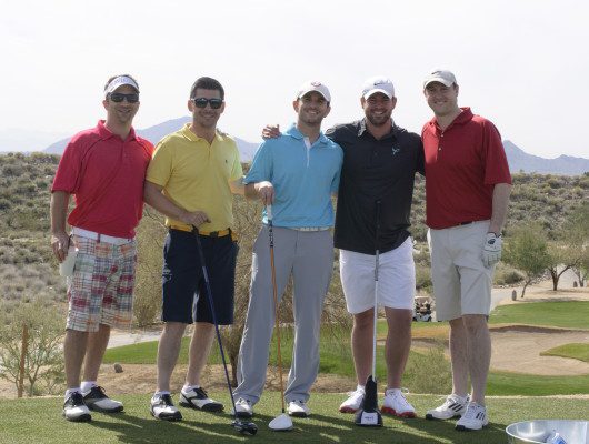 Five men posing on a golf course.