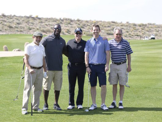 Five men posing on a golf course.