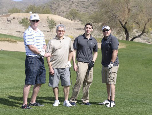Four men standing on a golf course.