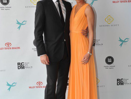 Couple posing at formal event backdrop.