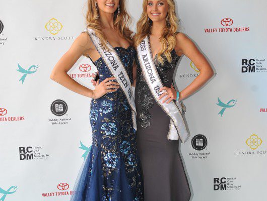 Two women in formal gowns with sashes.