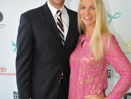 Man and woman posing at event backdrop.