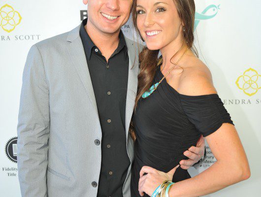 Smiling couple posing at event backdrop.