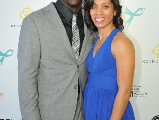 Smiling couple posing at event backdrop.