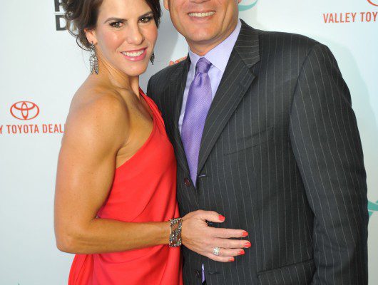 Couple posing at formal event backdrop.