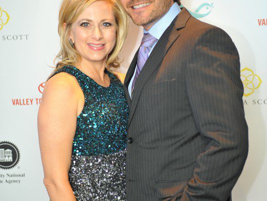 Couple posing at formal event backdrop.